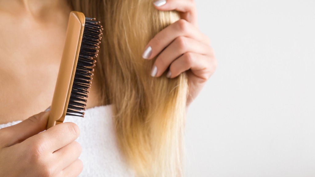 Womans hand brushing blonde hair cares about a healthy and clean hair picture id852239992